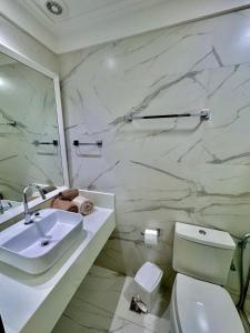 a white bathroom with a sink and a toilet at Ondina Apart Hotel Residences in Salvador