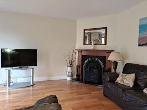 a living room with a black couch and a fireplace at Donard View, Newcastle in Newcastle
