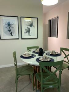 a dining room with a table and green chairs at Apartamento na Batista Campos 02 quartos in Belém