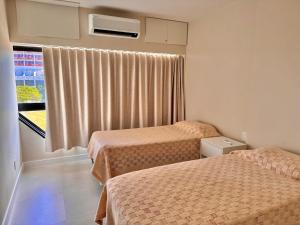 um quarto de hotel com duas camas e uma janela em Ondina Apart Hotel Residences em Salvador