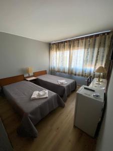 ブラガンサにあるSão Roque Hotel & Suitesのベッドルーム1室(ベッド2台、ランプ付きテーブル付)