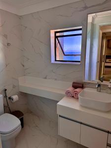 a bathroom with a sink and a toilet and a mirror at Ondina Apart Hotel Residences in Salvador