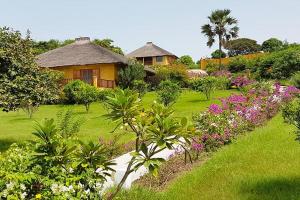 un jardin fleuri et une maison en arrière-plan dans l'établissement Ocean Lodge Resort, à Cap Skirring
