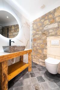 a bathroom with a sink and a stone wall at Casa del Sol Suites in Rhodes Town