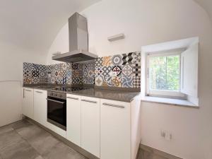 a kitchen with white cabinets and a stove and a window at Appartamento del centro in Lerici