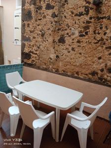 une table et des chaises blanches devant un mur dans l'établissement T3-HELTYMIE-terrasse-4 pers-idéal famille-parking gratuit-5 min des plages, à Portiragnes