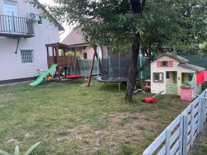 un patio trasero con un árbol y un parque infantil en Renáta Apartman, en Siófok