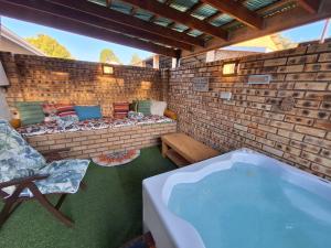 a patio with a jacuzzi tub in a brick wall at Windsong Living - Eagle Owl in Krugersdorp