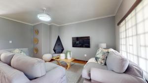 Una sala de estar con dos sofás blancos y una mesa. en Seas the Day - 3 Bedroom House, en Scottburgh