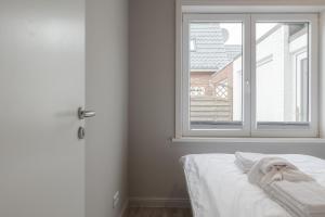 a white bedroom with a window and a bed at Appartement Krabbe - Haus Neptun in Westerland (Sylt)