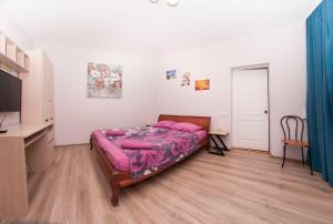 a bedroom with a bed with pink sheets and a television at apartments on Chkalova in Dnipro