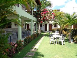 un patio con mesa, sillas y flores en Pousada Costa do Sol, en Tamandaré