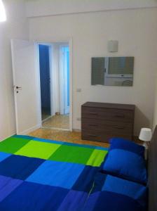 a bedroom with a blue and green bed and a dresser at Appartamento Ostia Enjoy in Lido di Ostia