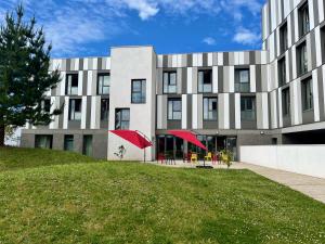 a building with a green lawn in front of it at Premiere Classe Le Havre Centre-LES DOCKS in Le Havre
