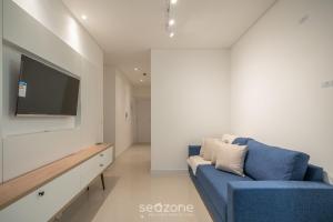 a living room with a blue couch and a flat screen tv at Apto 3Q c/ piscina e acad. 180m - LTT803 in Piçarras