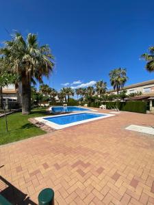 una piscina en un patio con palmeras en Río Palancia, Disfruta de una estancia en Familia en Oropesa del Mar