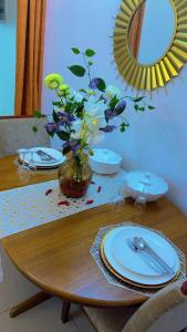 a table with plates and a vase with flowers on it at Caleb’s home in Douala +2 photos