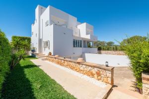een groot wit huis met een stenen muur bij Casa La Siesta in Cala d´Or