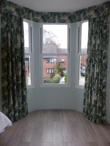 a living room with two windows and a wooden floor at Hamilton Court Hotel in Chester