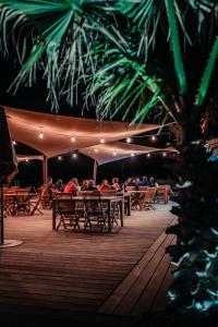 um grupo de pessoas sentadas a mesas num convés à noite em Nova Lodges em Grimaud