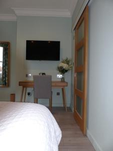 een slaapkamer met een bureau en een televisie aan de muur bij Hamilton Court Hotel in Chester