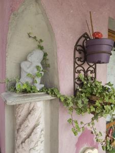 une statue assise sur une étagère avec une plante dans l'établissement Petit Paradis Croneuva, à Strasbourg