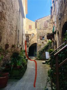 Un callejón con una manguera roja en un edificio. en Casa Lucilla, en Pitigliano
