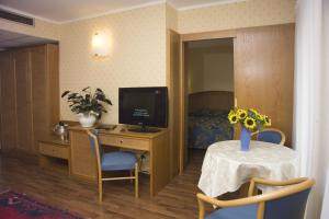 a room with a table and a television and a bed at Hotel Metropole in Grado
