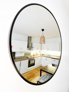 a mirror reflecting a kitchen with white cabinets and a table at Minimalistic apartment in Crystal Palace in Crystal Palace