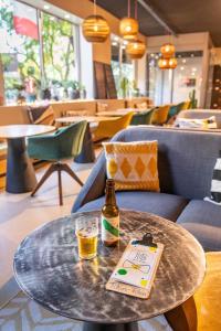 a bottle of beer sitting on a table with a drink at ibis Styles Paris 16 Boulogne in Paris