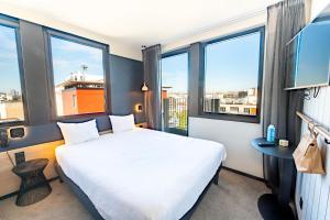 una camera d'albergo con un letto e ampie finestre di ibis Styles Paris 16 Boulogne a Parigi