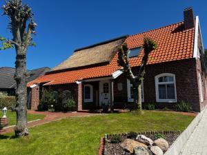 a brick house with an orange roof at Lindenhuus-Urlaub unter einem Teilreetdach-Terrasse - Nahe Norden-Norddeich in Osteel