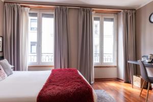 a bedroom with a bed with a red blanket on it at Hotel George Sand Opéra Paris in Paris