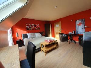 a bedroom with red walls and a bed and a table at B&B Herberg Boerenhol in Poperinge