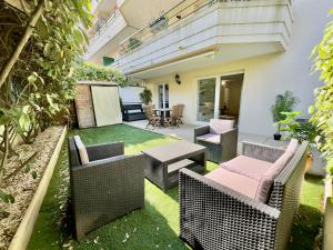 un cortile con sedie e tavoli in vimini e un patio di Regent Côte d'Azur air-conditioned, pool, garden & parking a Villeneuve-Loubet