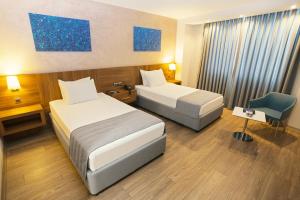 um quarto de hotel com duas camas e uma cadeira em Fesa Business Hotel em Gebze