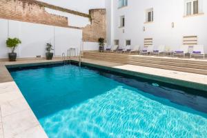 a swimming pool in a building with blue water at Eurostars Sevilla Boutique in Seville