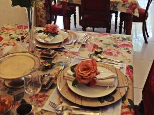 una mesa con platos y vasos y una rosa en ella en Victorian Manor Guesthouse en Frankfort