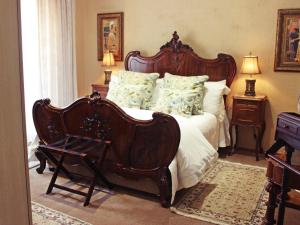 a bedroom with a large wooden bed and a chair at Victorian Manor Guesthouse in Frankfort