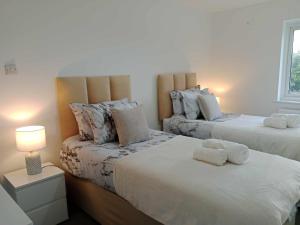 um quarto com 2 camas e toalhas em Monmouth House Aylesbury Premier Quality Accommodation For Contractors Professionals and Larger Families Sleeps Up to 6 Guests em Buckinghamshire