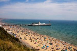 a crowd of people on a beach with a pier at Student Only Ensuite Rooms Zeni Bournemouth in Bournemouth