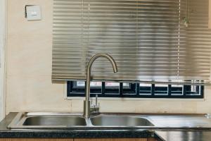 um lavatório numa cozinha com uma janela em Epignosis Apartments em Lusaka