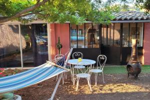 a hammock and a table and chairs in front of a building at LE CABANON Piscine Jacuzzi Sauna Paillote in La Seyne-sur-Mer