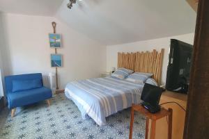 a bedroom with a bed and a blue chair and a tv at LE CABANON Piscine Jacuzzi Sauna Paillote in La Seyne-sur-Mer