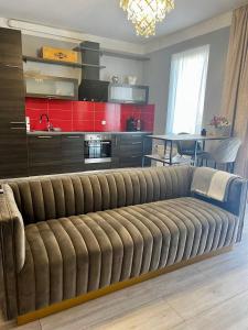 ein großes Sofa im Wohnzimmer mit Küche in der Unterkunft LK Apartment in Mārupe