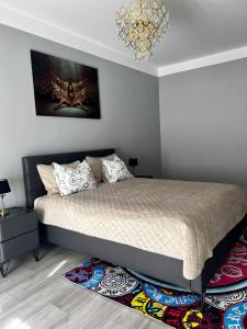 1 dormitorio con 1 cama con lámpara de araña y alfombra en LK Apartment, en Mārupe