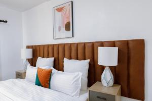 a bed with a wooden headboard and two lamps on tables at Epignosis Apartments in Lusaka