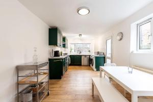 a kitchen with green cabinets and a table at Modern Victorian Home with Secret Garden in London