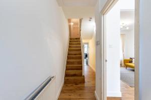 a staircase in a home with white walls and wooden floors at Modern Victorian Home with Secret Garden in London
