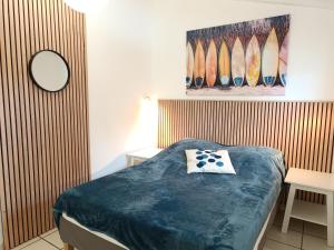 a bedroom with a bed and a painting of surfboards at T2 climatisé à 2 minutes de la plage du Pont Tournant - 4BRANR in Saint Cyprien Plage